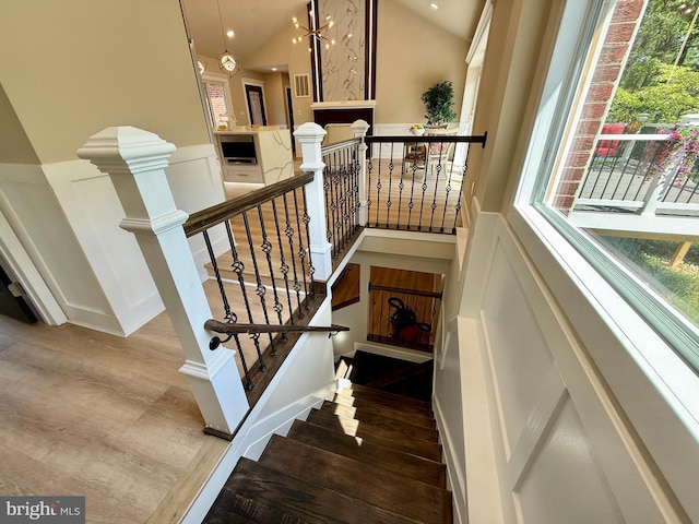 9905 Stoughton Rd, Fairfax, VA 22032 - staircase featuring a decorative wall, high vaulted ceiling, wainscoting, and wood finished floors