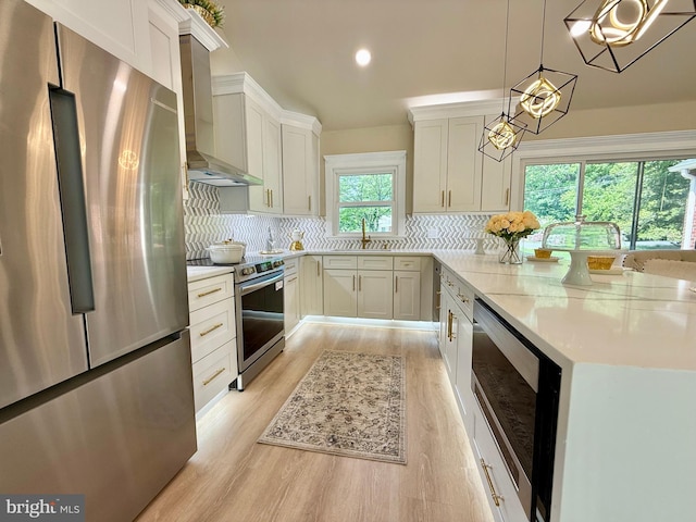 9905 Stoughton Rd, Fairfax, VA 22032 - kitchen featuring a peninsula, light wood-style flooring, stainless steel appliances, wall chimney range hood, and tasteful backsplash