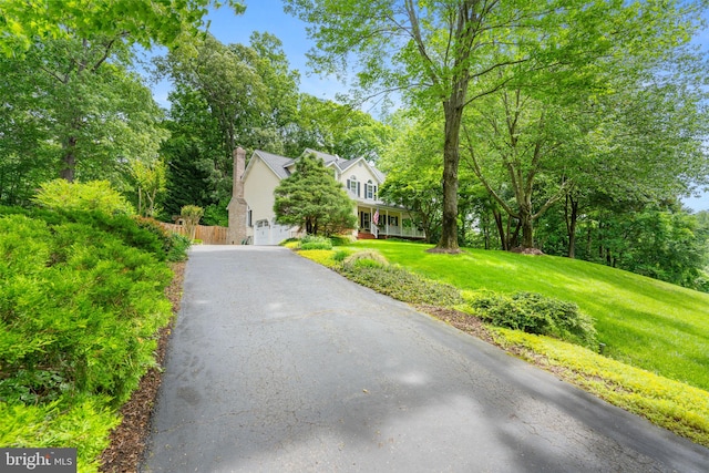 3635 Wessex Ln, Huntingtown, MD 20639 - view of front facade with driveway, a garage, a chimney, and view of wooded area