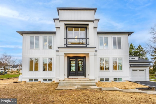 view of front of property featuring board and batten siding, french doors, a balcony, aphalt driveway, and entry steps