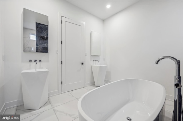 bathroom featuring baseboards, a soaking tub, and marble finish floor