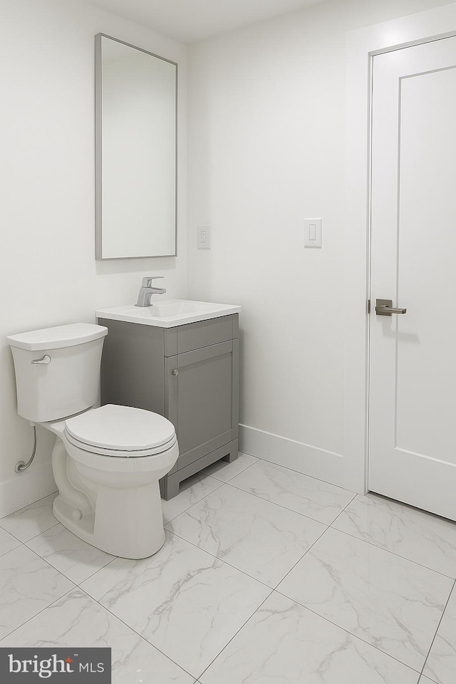 bathroom with baseboards, vanity, toilet, and marble finish floor