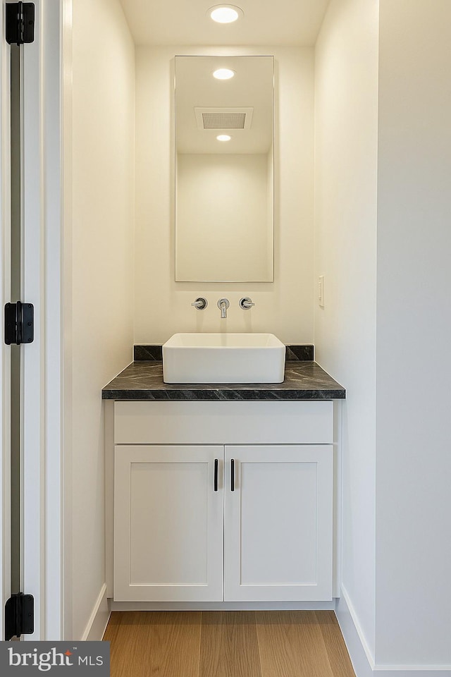 bathroom featuring visible vents, baseboards, wood finished floors, and vanity