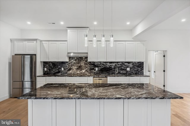 kitchen with tasteful backsplash, freestanding refrigerator, under cabinet range hood, and light wood finished floors