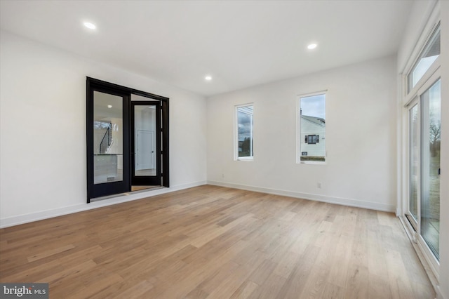 spare room featuring recessed lighting, baseboards, and light wood finished floors