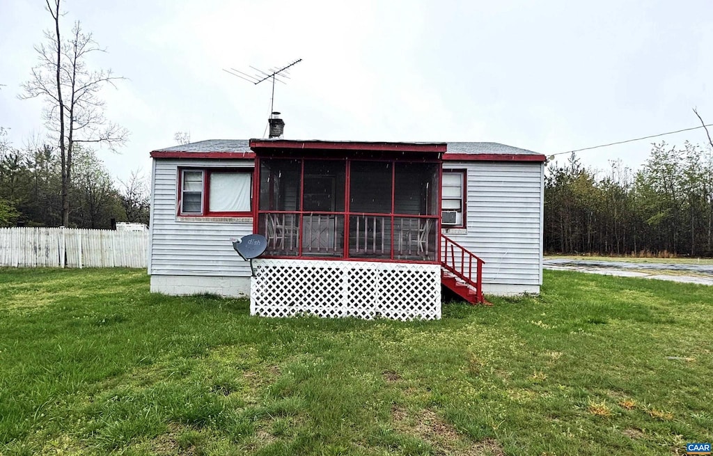 back of house featuring a sunroom, fence, and a yard