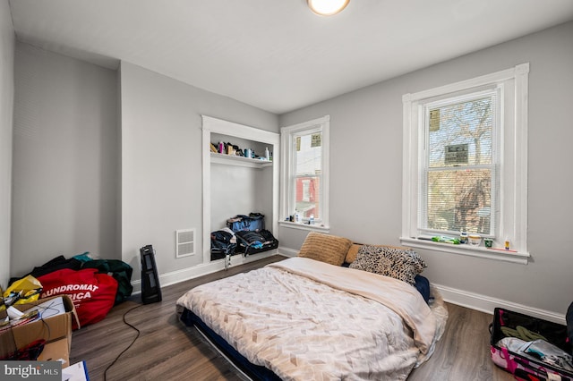 bedroom with baseboards, wood finished floors, and visible vents