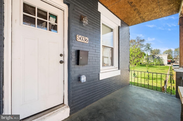property entrance featuring brick siding and a porch