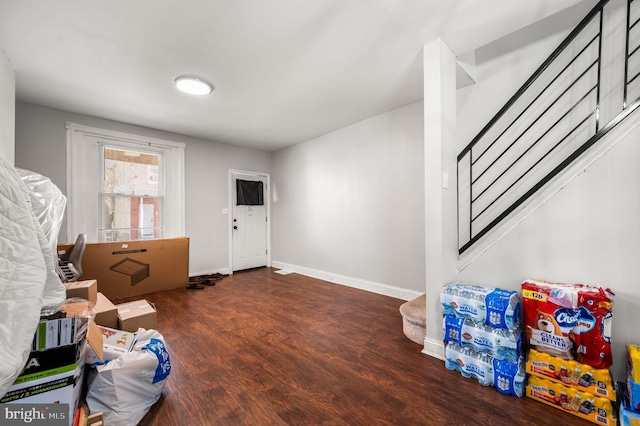 foyer featuring baseboards, wood finished floors, and stairway