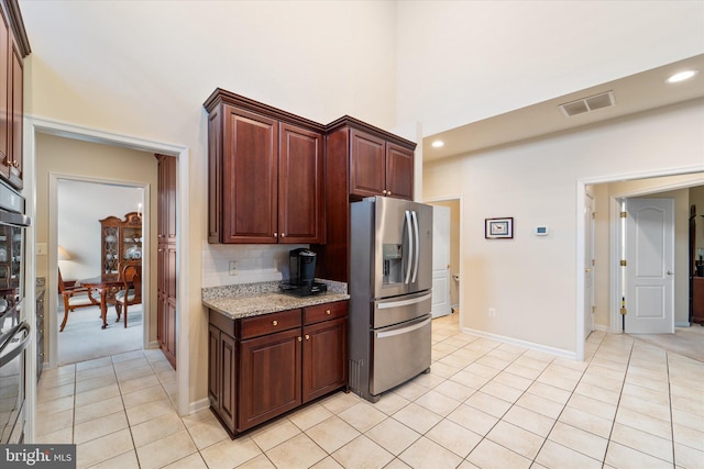 44516 Blueridge Meadows Dr, Ashburn, VA 20147 - kitchen featuring visible vents, a towering ceiling, stainless steel refrigerator with ice dispenser, light stone counters, and light tile patterned floors