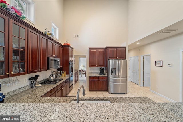 44516 Blueridge Meadows Dr, Ashburn, VA 20147 - kitchen with decorative backsplash, glass insert cabinets, a high ceiling, a sink, and stainless steel appliances