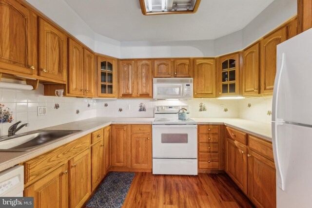 kitchen featuring a sink, dark wood-style flooring, white appliances, and brown cabinetry