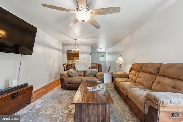 living room with ceiling fan with notable chandelier and wood finished floors