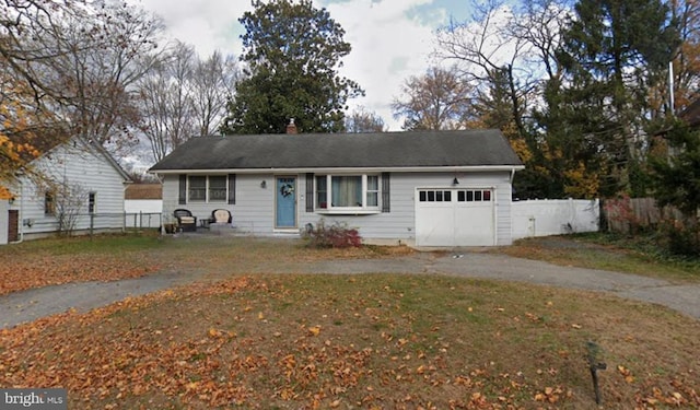 view of front of house featuring an attached garage, fence, driveway, and a chimney