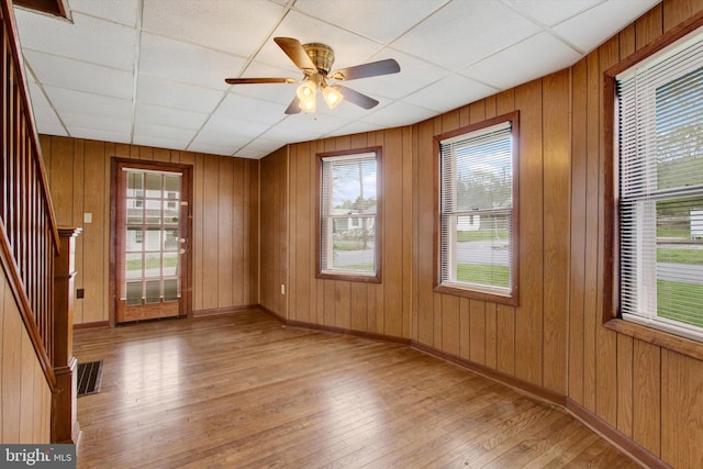 empty room featuring stairway, visible vents, hardwood / wood-style flooring, and a wealth of natural light