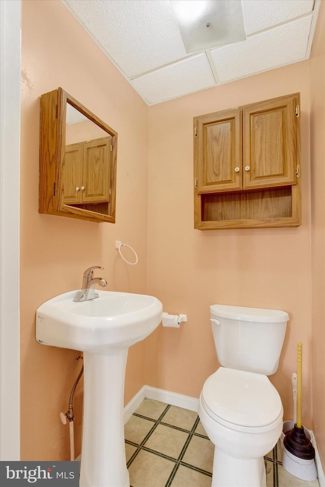 bathroom featuring baseboards, tile patterned flooring, and toilet