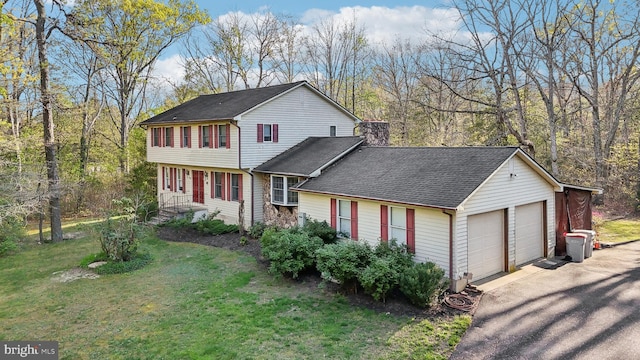 view of front facade with a detached garage, roof with shingles, a chimney, and a front yard