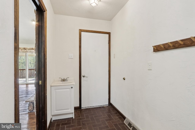 doorway to outside featuring brick patterned floor and a sink