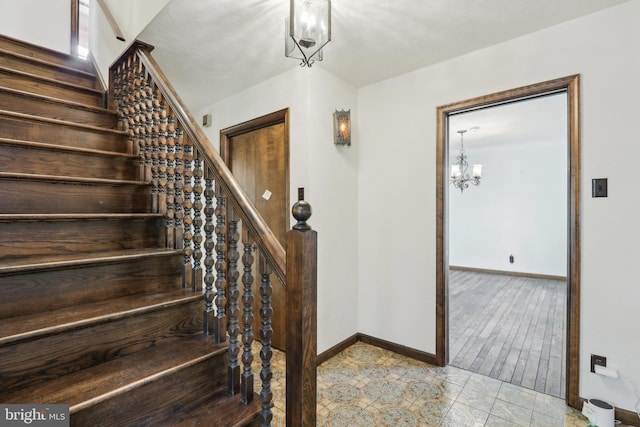 stairway featuring baseboards and a notable chandelier