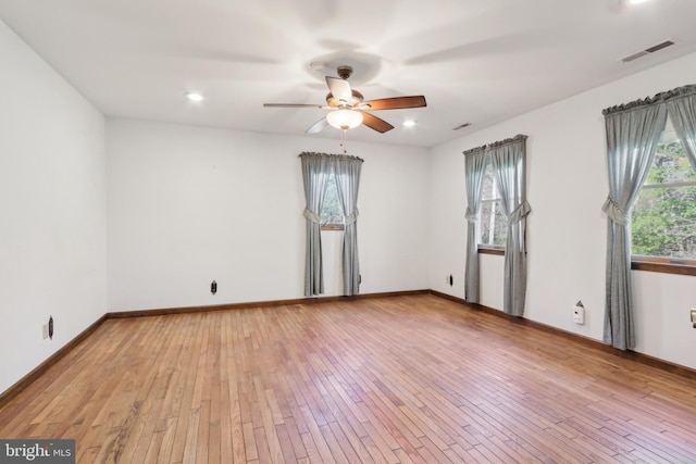 empty room with ceiling fan, visible vents, baseboards, and light wood finished floors