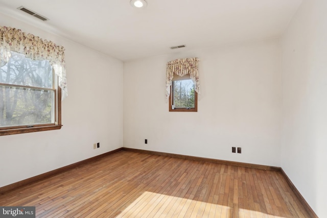 empty room featuring baseboards, wood-type flooring, and visible vents