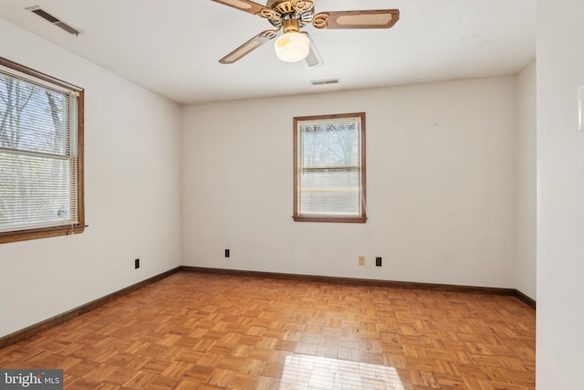 empty room with a healthy amount of sunlight, baseboards, and visible vents