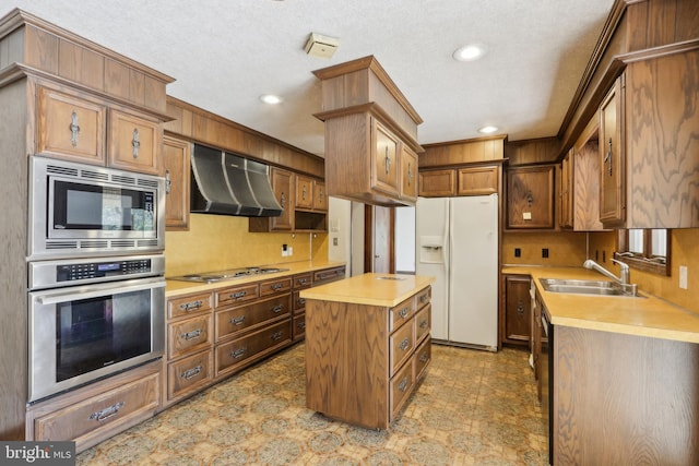kitchen featuring appliances with stainless steel finishes, a sink, ventilation hood, light countertops, and a center island