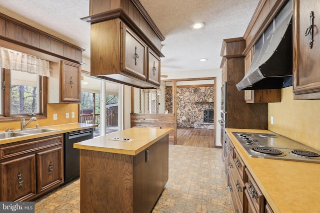 kitchen with a sink, light countertops, a textured ceiling, stainless steel appliances, and under cabinet range hood