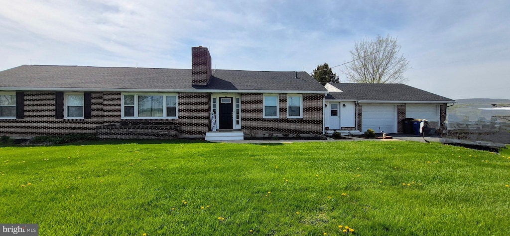 ranch-style home with a garage, a chimney, brick siding, and a front yard