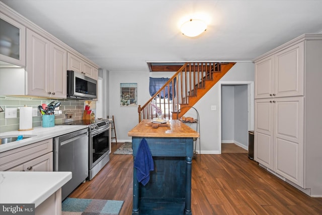 kitchen with light countertops, appliances with stainless steel finishes, tasteful backsplash, and dark wood finished floors