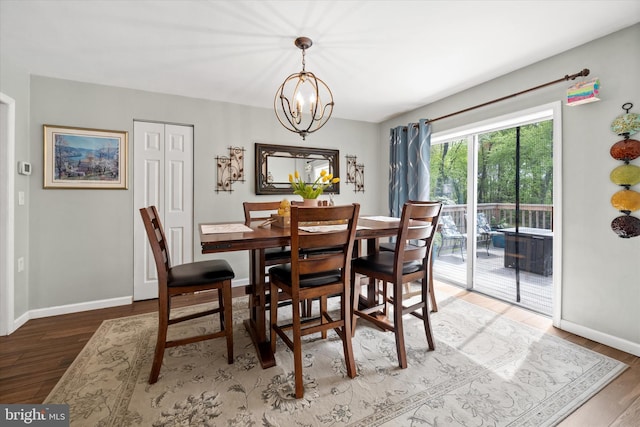 dining area with baseboards, wood finished floors, and a notable chandelier