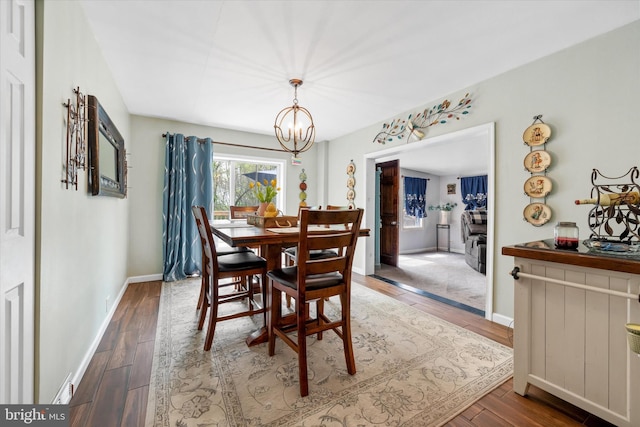 dining area featuring baseboards, a chandelier, and wood finished floors