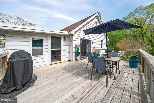 wooden terrace with outdoor dining area and grilling area