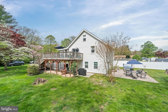 rear view of house with a wooden deck, fence, a patio, stairs, and a lawn