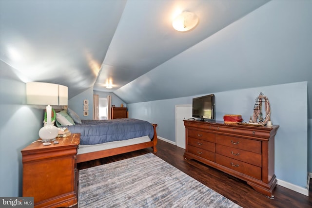 bedroom featuring baseboards, wood finished floors, and vaulted ceiling