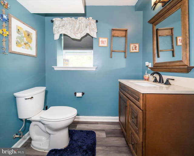 half bathroom featuring baseboards, vanity, toilet, and wood finished floors
