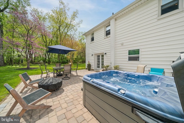 view of patio / terrace with a hot tub, a fire pit, outdoor dining space, and french doors