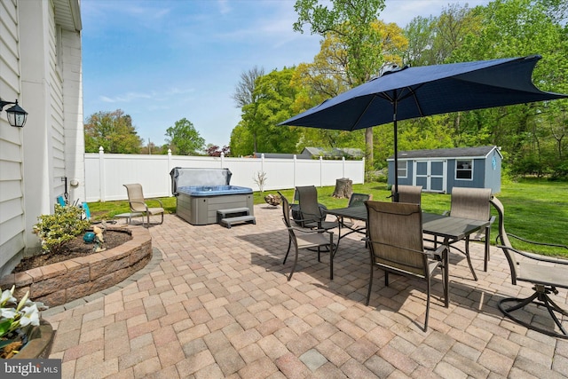 view of patio / terrace featuring outdoor dining area, an outbuilding, a hot tub, a fenced backyard, and a storage unit