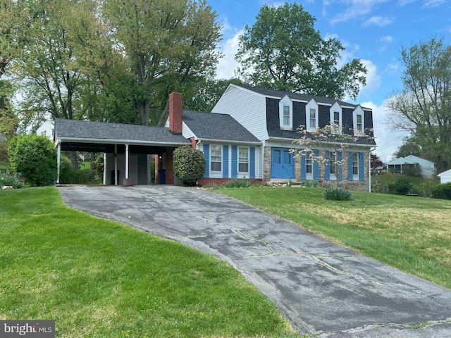 view of front of home featuring a chimney, an attached carport, a front yard, and aphalt driveway