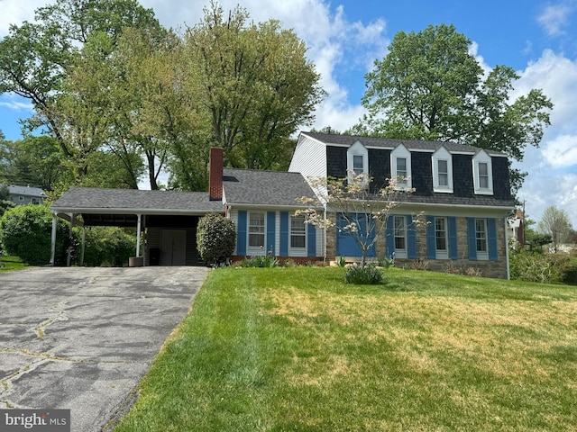 view of front facade with roof with shingles, a front lawn, an attached carport, a chimney, and driveway