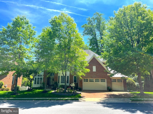 view of property hidden behind natural elements with brick siding, concrete driveway, and an attached garage