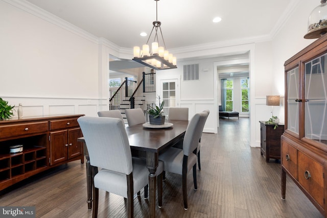 dining room with a decorative wall, a chandelier, dark wood finished floors, stairway, and crown molding