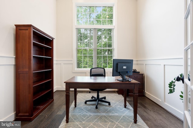 office area with a decorative wall, plenty of natural light, dark wood-style flooring, and a wainscoted wall