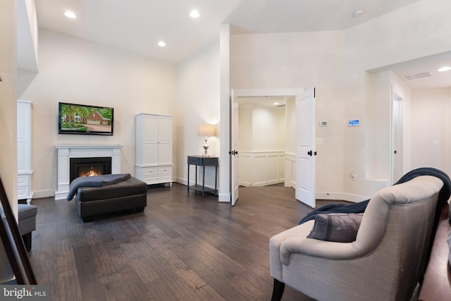 living room featuring dark wood-style flooring, a warm lit fireplace, recessed lighting, and baseboards