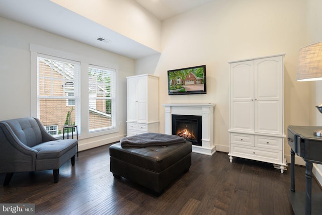 living area with dark wood-style floors, a lit fireplace, and baseboards