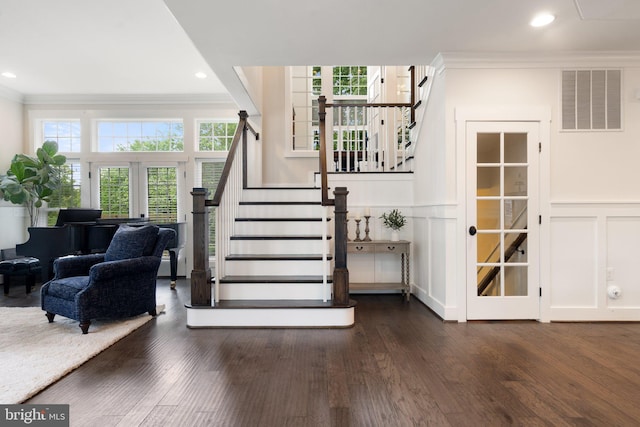 stairs featuring crown molding, a decorative wall, wood finished floors, a wainscoted wall, and recessed lighting