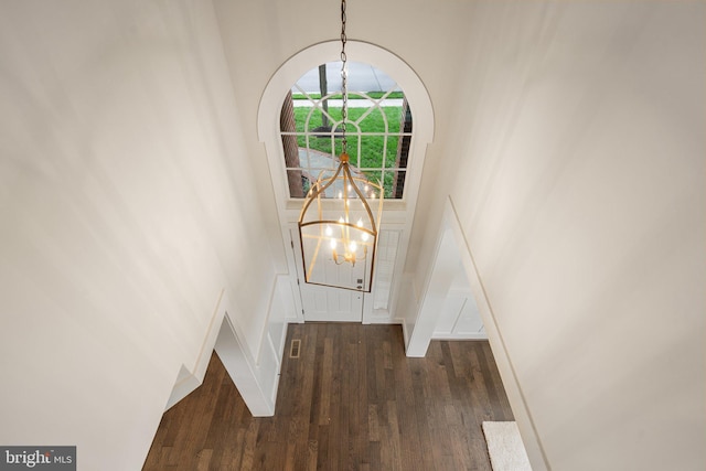 staircase featuring a chandelier, wood finished floors, and a towering ceiling
