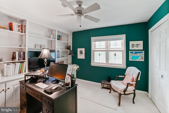 home office with baseboards, a ceiling fan, and light colored carpet