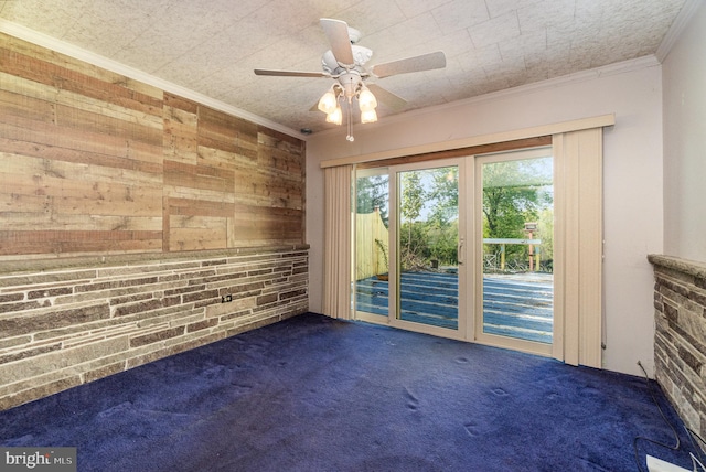 empty room with carpet flooring, ceiling fan, wood walls, and crown molding