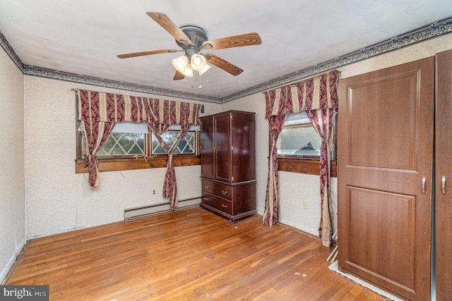 unfurnished room featuring ceiling fan, a baseboard heating unit, and wood finished floors